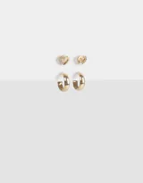 Set de dos pares de aros bañados en oro: un par de aros pasantes con forma de corazón y strass, y un par de argollas pequeñas.