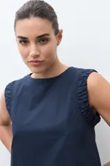 Blusa roja sin mangas, con cuello redondo y sisa drapeada.