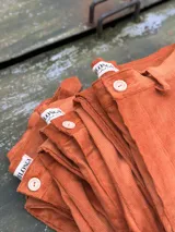 Pantalón de pana color ladrillo, con corte recto y cierre con botón.