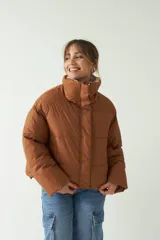 Campera puffer color marrón con cuello alto, corte cropped a la cadera, cierre metálico y botones.