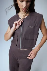 Chaleco corto color marrón confeccionado en gabardina con cierre metálico frontal, bolsillos con fuelle y badana de PU en la espalda.