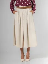 Falda midi de corderoy color beige claro, con pliegues verticales marcados y cintura elastizada. Incluye un cinturón desmontable de cuero marrón con hebilla dorada.