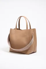 Bolso tote negro de cuero vacuno con doble asa corta y correa de tela extraíble. Interior con tres compartimentos y bolsillo con cremallera. Logo metálico de la marca en el frente.