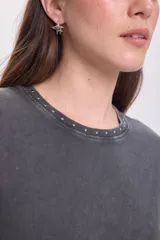 Remera gris oscuro con cuello redondo y tachas plateadas alrededor del cuello.