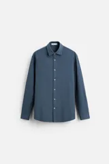 Camisa de vestir azul petróleo, corte regular, confeccionada en mezcla de algodón. Cuenta con cuello solapa, mangas largas con puños abotonados y cierre frontal con botones.