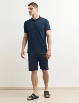 Chomba azul marino con pequeños lunares blancos, cuello clásico con botones y mangas cortas.