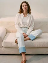 Jean de algodón de tiro medio, color celeste muy claro, con un dobladillo ancho y contrastante en color azul claro en los tobillos. El corte es recto o ligeramente holgado.