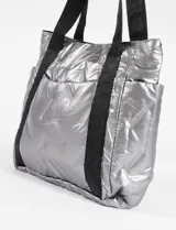 Bolso tipo tote bag color negro metalizado, con asas de hombro de largo medio y bolsillos laterales.