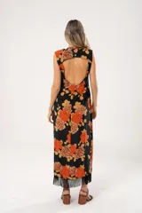 Vestido midi negro con estampado de flores naranjas y beige, espalda descubierta con tres botones en forma de flor, tajo lateral y flecos en el ruedo.
