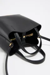 Bolso tote pequeño de cuero sintético color negro con doble asa de mano y correa bandolera ajustable y extraíble. Logotipo de la marca en letras doradas en la parte frontal.