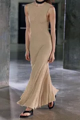 Vestido midi de encaje color beige, sin mangas, con espalda descubierta y bajo asimétrico con volados.