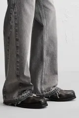 Pantalón de jean negro con efecto lavado, corte flare, cinco bolsillos, cierre frontal con cremallera y botón, y bajo con acabado irregular.
