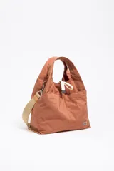 Bolso de mano Bimba y Lola color ladrillo, de nailon con estructura blanda, doble asa de mano y asa de tejido regulable. Cuenta con logo metálico BIMBA Y LOLA, acabados metálicos, bolsillo interior, cierre de cordón e interior con etiqueta de tejido.