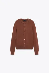 Chaqueta marrón de punto con cuello redondo decorado con abalorios tipo joya y manga larga. Cierre frontal con botones.