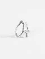 Anillo plateado de aleación de metales con diseño abierto y líneas fluidas.