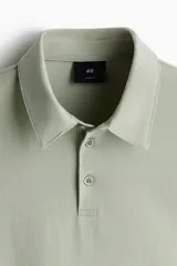 Remera polo verde claro en tejido de punto de algodón liviano, de corte ajustado, con cuello clásico, tapeta de botones y mangas cortas.
