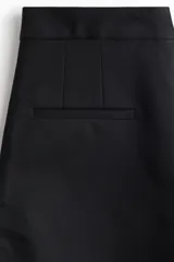 Short negro de tiro alto con cierre y pretina prolongada con botón. Modelo con bolsillos al bies y bolsillos insertados decorativos atrás.