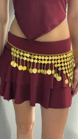 Caderín dorado con cadenas y monedas colgantes.