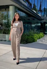 Conjunto color beige compuesto por un blazer corto con solapas de muesca, mangas cortas y un botón de cierre, combinado con un pantalón de vestir de corte recto.