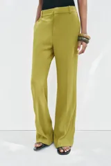 Pantalón de vestir color verde oliva, de tiro medio, corte flare y bolsillos laterales.