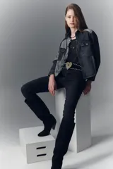 Campera recta de denim rígido negro con recortes en gris. Tiene bolsillos con solapa y botones metálicos.