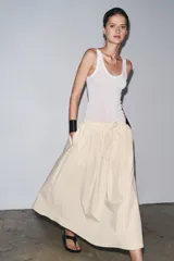 Falda midi de Zara Woman Collection confeccionada en hilatura de algodón color crudo con finas rayas verticales marrones. Tiene tiro medio, cintura elástica ajustable con cordones y bajo evasé.