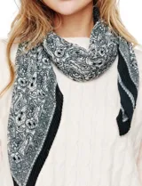 Pañuelo cuadrado de poliéster plisado, color blanco roto, con estampado paisley en tonos malva y gris. Presenta un borde liso en tono malva oscuro.