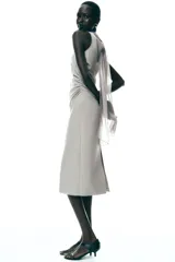 Vestido midi color gris topo, de cuello halter con lazada combinada a tono. Bajo con abertura en espalda. Cierre en espalda con cremallera, abertura y botón.