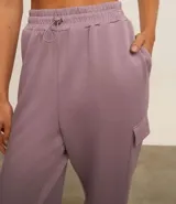 Pantalón deportivo color lila, confeccionado en microfibra pesada con viscosa certificada. Cuenta con cintura elástica ajustable, bolsillos cargo laterales y ajuste en el bajo.