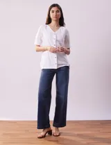 Blusa blanca de algodón con escote en V, abertura con botones y mangas cortas con detalle de broderie.