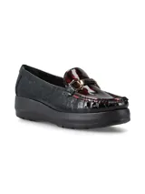 Mocasín de cuero charol negro con plataforma blanca y detalle de hebilla metálica plateada en el empeine.