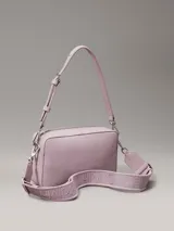 Bandolera Calvin Klein modelo Must, color lila, con correa ajustable y logo plateado en el frente. Incluye bolsillo exterior con cierre y bolsillo interior.