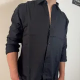 Camisa blanca de lino con corte regular, cuello clásico y mangas largas con puños abotonados.