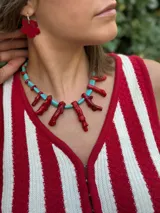 Collar corto con cuentas de color turquesa y dijes de coral rojo. Cierre con cadena de acero quirúrgico y ganchito para regular el largo.