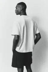 Remera color crema de corte holgado, con cuello redondo y mangas cortas.