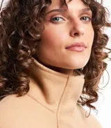 Saco color beige en polyvelour, con cuello alto, mangas largas, sisas desplazadas, cierre delantero y bolsillos con detalle en PU.