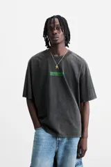Camiseta gris oscuro con efecto lavado, cuello redondo, manga corta y estampado de textos combinados en verde neón en el delantero y la espalda.