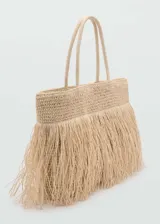Bolso tipo shopper color beige, tejido en fibra natural con detalle de flecos. Tiene doble asa de mano, cierre con botón magnético y bolsillo interior.