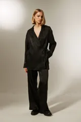 Blusa negra con corte cruzado, escote en V, mangas largas y lazo lateral para ajustar.