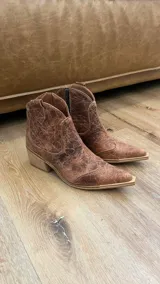 Bota texana de caña baja color marrón con efecto vintage, confeccionada en cuero vacuno y forrada en cuero. Tiene taco de 5cm y cierre lateral.
