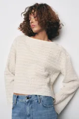 Top mostaza de cuello barco y manga larga con textura. Tiene lazadas ajustables en el bajo.