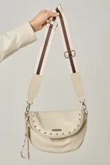 Bandolera de cuero celeste con correa de cinta regulable, forro de algodón, cierre central y bolsillo trasero con cierre.