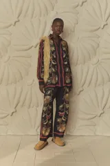 Pantalón negro con estampado floral en tonos naranja, amarillo y rojo. Corte holgado, cintura elástica de tiro medio y largo amplio.