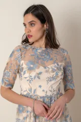 Vestido largo de gasa color marfil con bordado de hilo de seda en tonos celeste y avena. Modelo recto con corte en la cintura, manga corta y ruedo terminado en blonda.