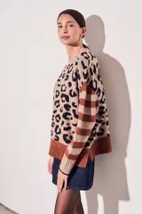 Sweater oversize con estampado animal print en tonos beige y negro, con mangas rayadas en color marrón.