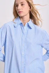 Camisa celeste a rayas verticales blancas, de manga larga con puños elásticos y volados en el frente.
