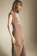 Vestido midi color beige con cuello solapa, escote en pico y manga corta. Cintura entallada con pliegues y cierre lateral con cremallera oculta.