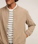 Campera bomber marrón de terciopelo pana con cuello redondo, cierre con botones a presión, bolsillos laterales, puños y cintura elastizados.