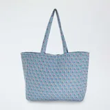 Bolso shopper acolchado de tela celeste con estampado de flores rosas y azules.