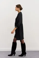 Minivestido negro de viscosa con corte en la cintura, detalles de puntillas en cuello y ruedo, gota en la espalda y pechera bordada en hilo con apliques.